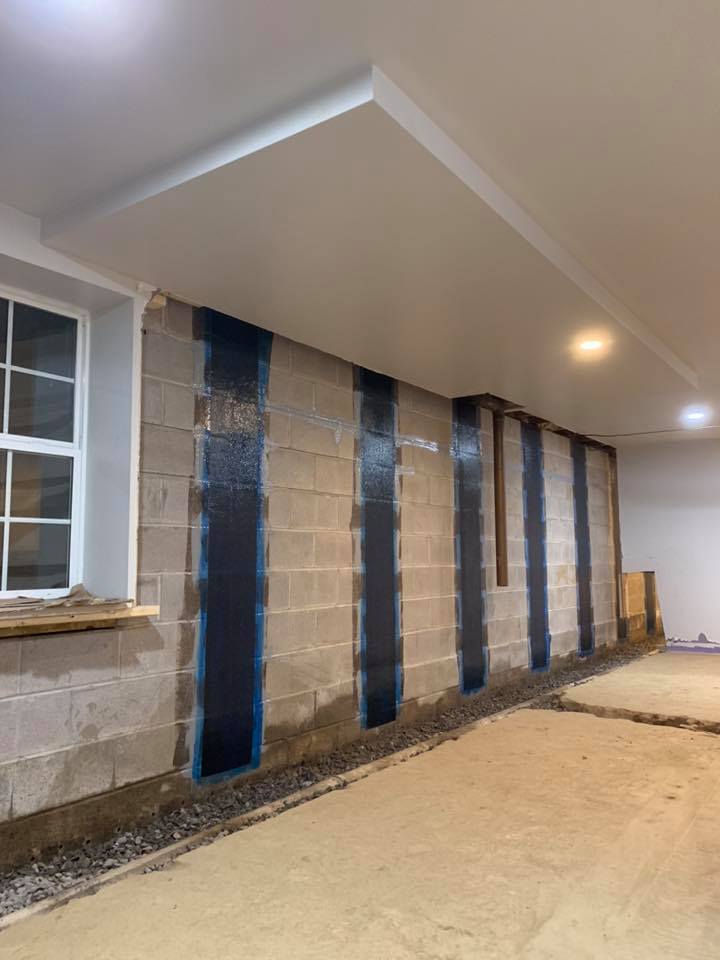 Basement wall with waterproofing system being installed